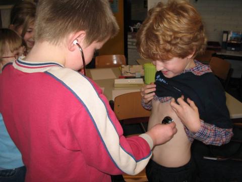 Kinderen onderzoeken elkaars hartslag met een echte stethoscoop.